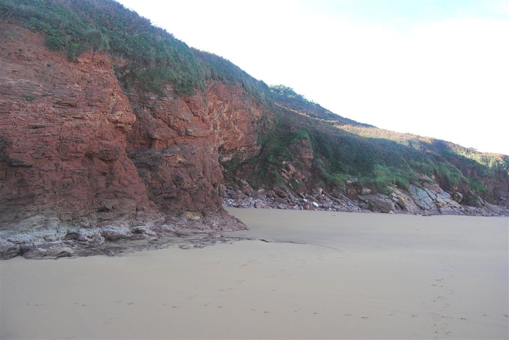 Discordancia angular entre las calizas devónicas del Complejo de Rañeces (a la derecha, al borde de la arena) y el Triásico (sobre las calizas y a la izquierda de la fotografía)