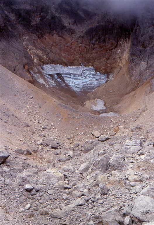 El helero con la morrena frontal y el depósito de bloques situado al N de la morrena. Se aprecian restos de neviza en el fondo del jou y el hielo aflora solamente adosado a la pared posterior.  Fecha: Octubre 1997. Autor: V. Alonso.