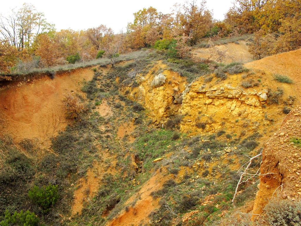 Aspecto del afloramiento de las calizas ocres y amarillas de la Formación Boñar, del Cretácico, en Brugos de Fenar. En la mitad izquierda de la imagen se reconocen los materiales paleógenos de la Formación Vegaquemada.