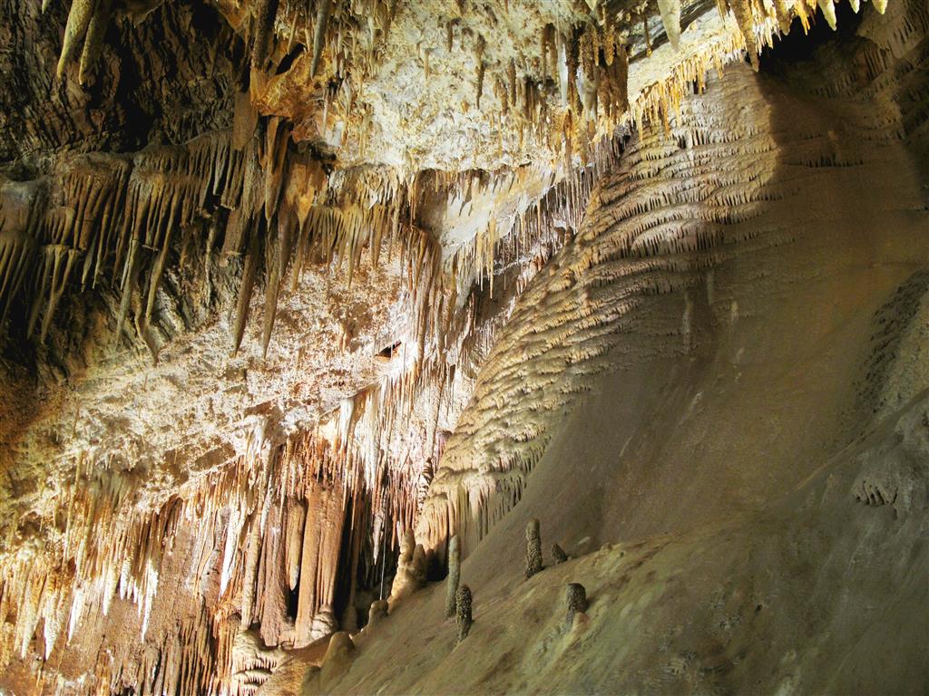 Panorámica general de la sala principal de la cueva de Valdelajo. Destaca la gran profusión de espeleotemas en ubicaciones muy diversas, así como la gran colada que cierra la sala por su lado derecho.