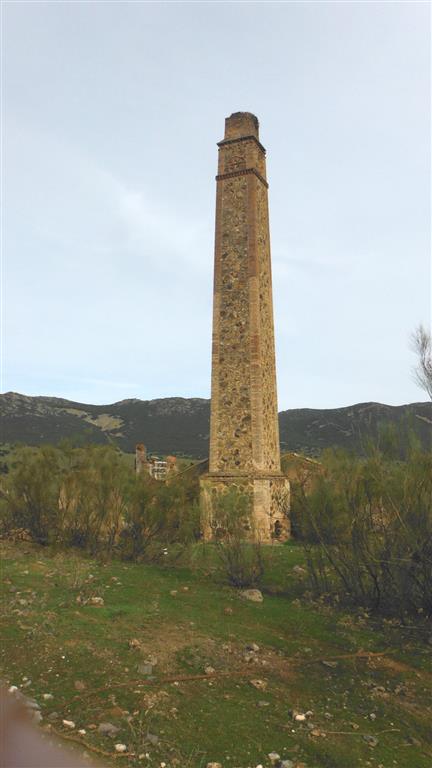 Mina El Burcio: chimenea de humos de la antigua máquina de vapor, que también puede verse en la foto anterior, próxima al pozo.