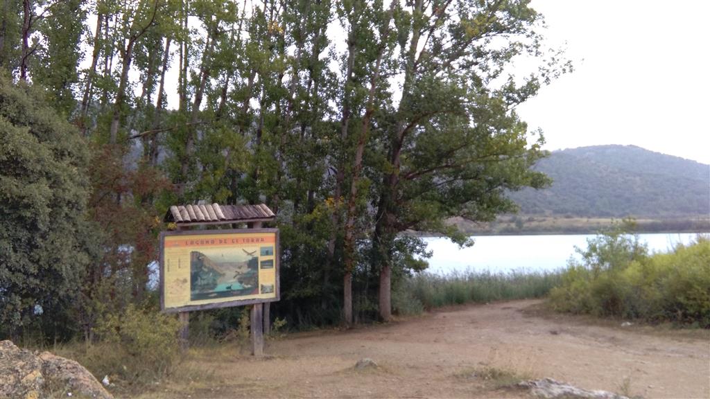 Fotografía de la Laguna Grande de El Tobar tomada el 14-9-2016 desde el final del camino que se dirige a la Laguna desde El Tobar. Se destaca la presencia de paneles informativos.