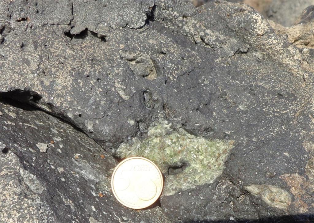 Detalle de un xenolito dunítico dentro del basalto (escala: moneda 5 céntimos).