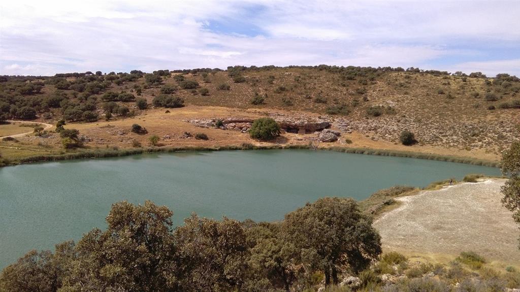 Fotografía de la Laguna del Arquillo tomada el 13-9-2016. En el centro se pueden ver las cuevas naturales que ya utilizaban los habitantes del Paleolítico como lugar de asentamiento y caza.