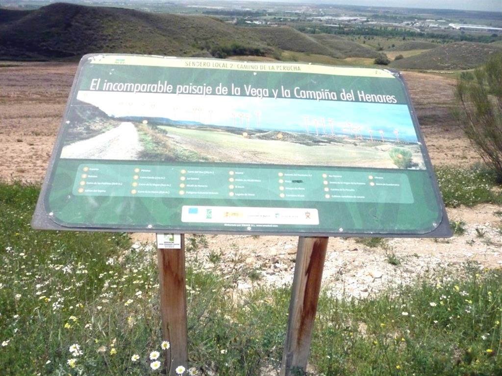 Panel explicativo de  La Vega y Campiña del Henares. Por encima del panel se visualizan diversas colinas que son restos de la superficie del glacis. Obsérvese su inclinación hacia el valle del Henares.          