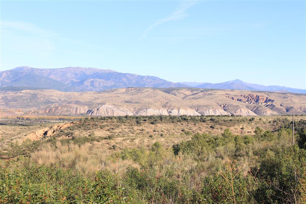 Vista general de los afloramientos paleógenos y de los depósitos miocenos suprayacentes. Al fondo los relieves paleozoicos de Somosierra- Sierra de Ayllón